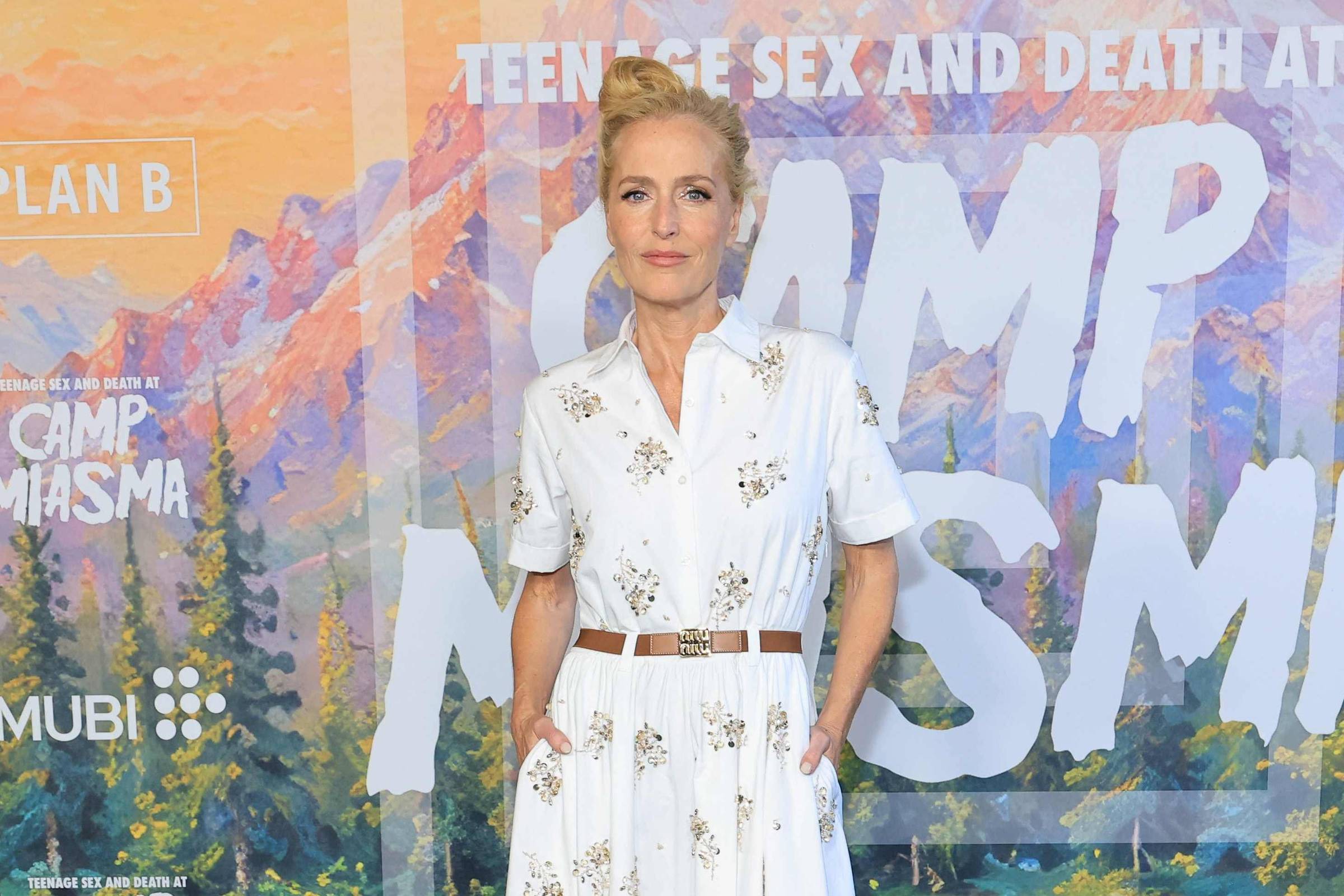 Gillian Anderson com vestido branco em tapete verde