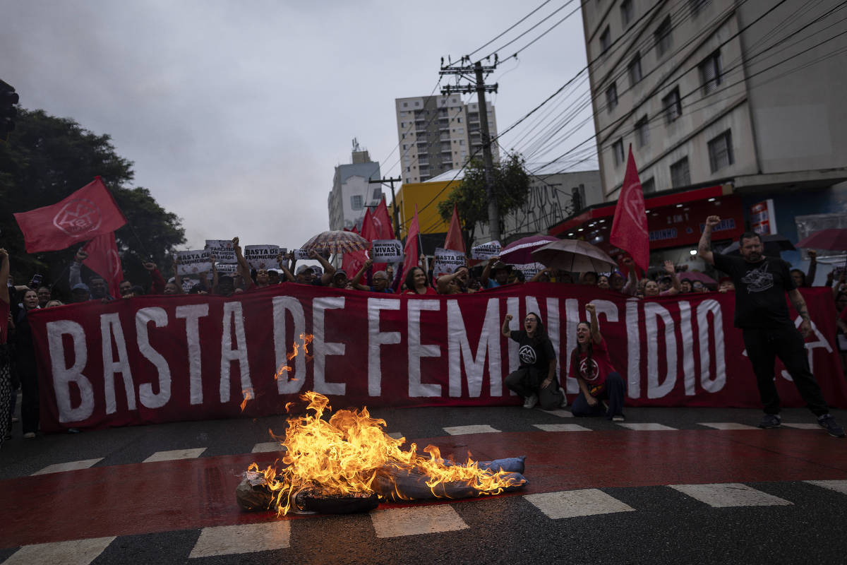 Manifestantes seguram faixa contra o feminicídio durante bloqueio de avenida