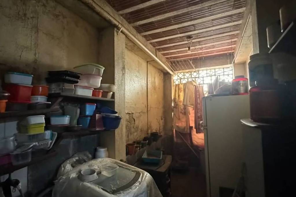 Dependência estreita com utensílios, geladeira e objetos empilhados em Belo Horizonte