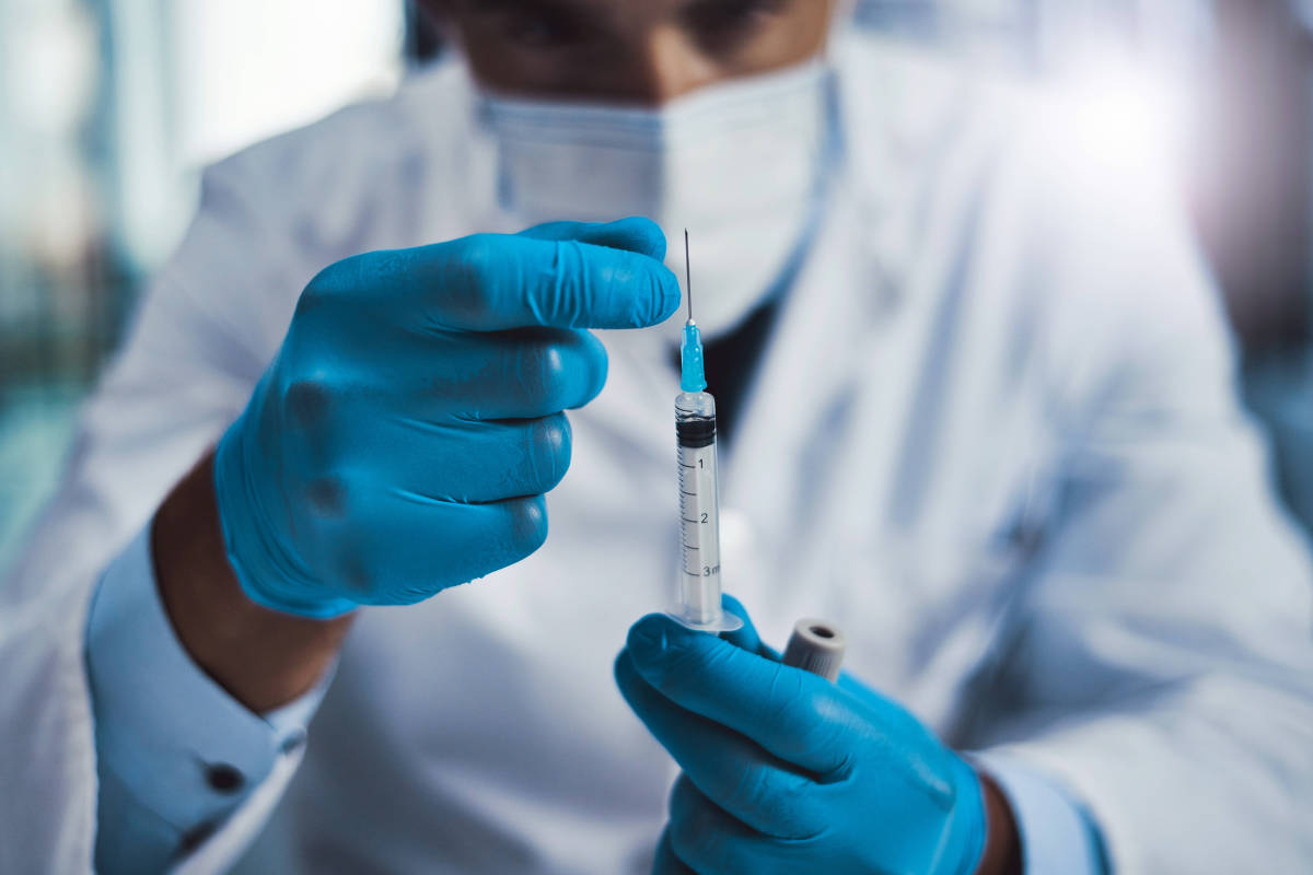Profissional de saúde prepara seringa em ambiente clínico
