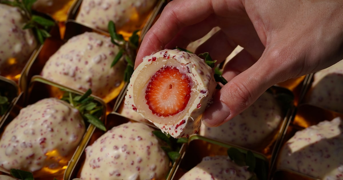 Morango cravejado coberto com chocolate branco e pedaços de calda vermelha