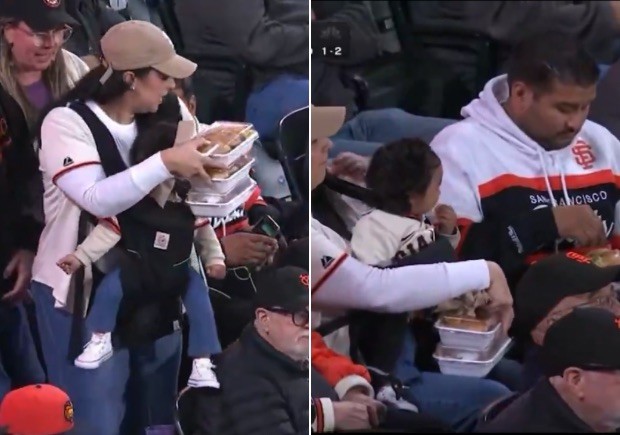 Mulher carrega bebê e bandejas de comida em estádio de beisebol