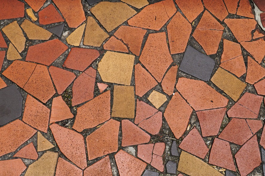Fragmentos coloridos de cerâmica formam piso de caquinhos