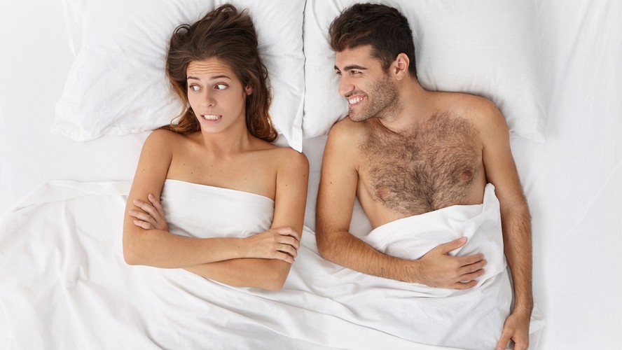 Casal sentado na cama visto de cima