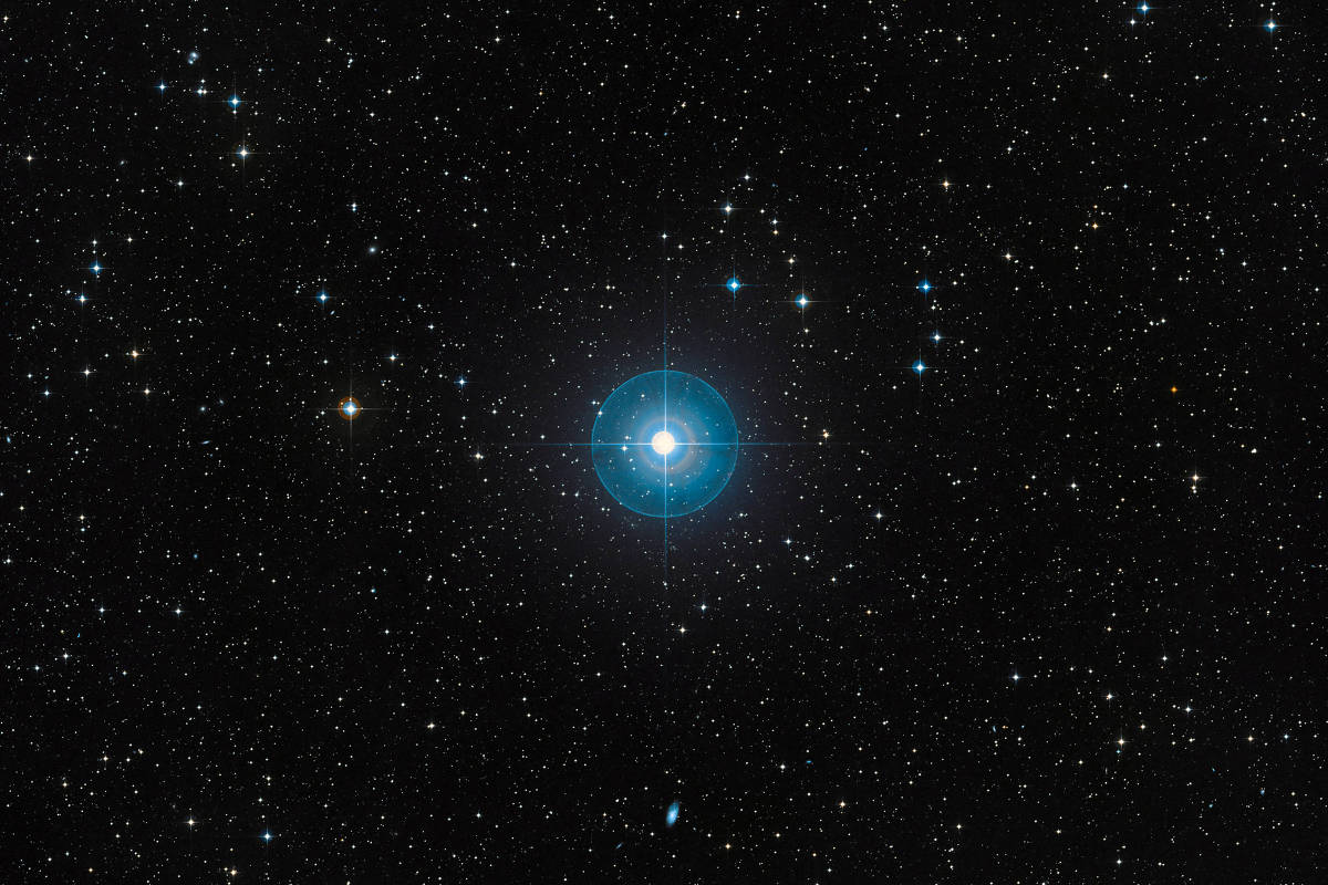 Estrela azul brilhante cercada por estrelas menores em fundo escuro