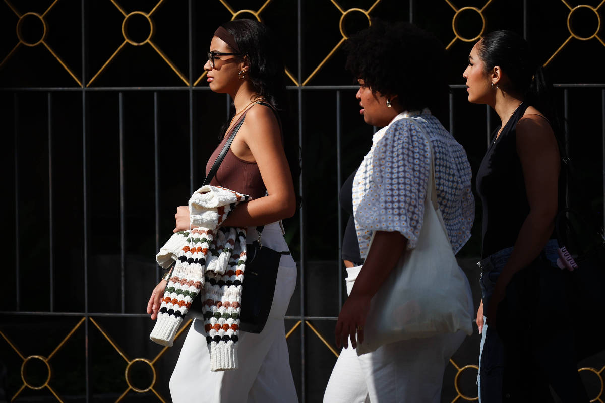 Três mulheres caminham por rua na região da avenida Paulista