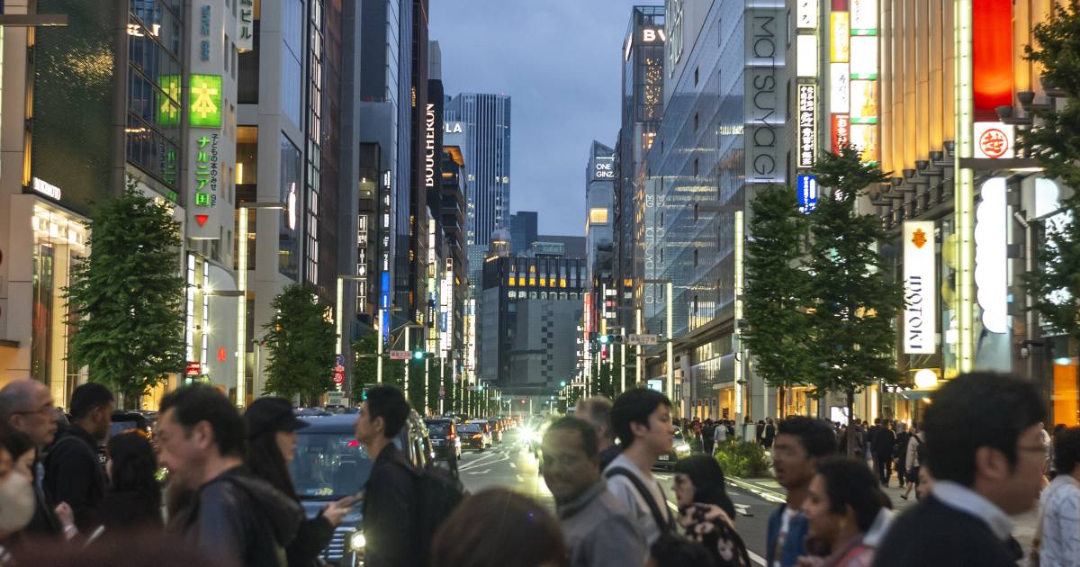 Pedestres caminham por rua comercial em Tóquio