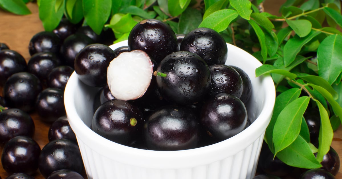 Jabuticabas em pote de louça com uma fruta aberta