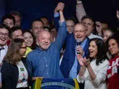 Lula e Geraldo Alckmin erguem os braços após a reeleição, cercados por apoiadores