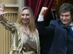 Javier Milei ao lado de Karina Milei diante de cortina vermelha