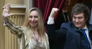Javier Milei ao lado de Karina Milei diante de cortina vermelha