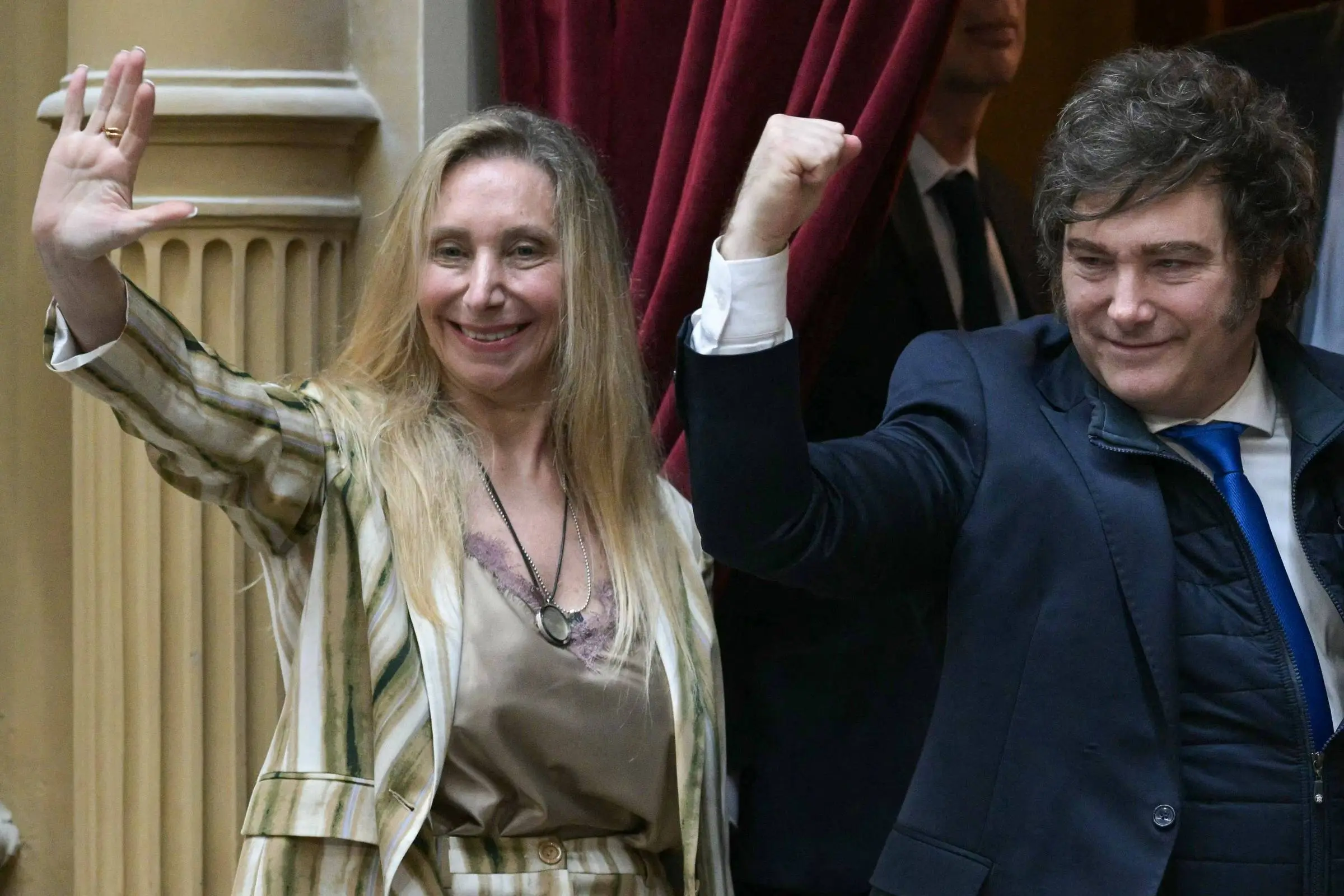 Javier Milei ao lado de Karina Milei diante de cortina vermelha