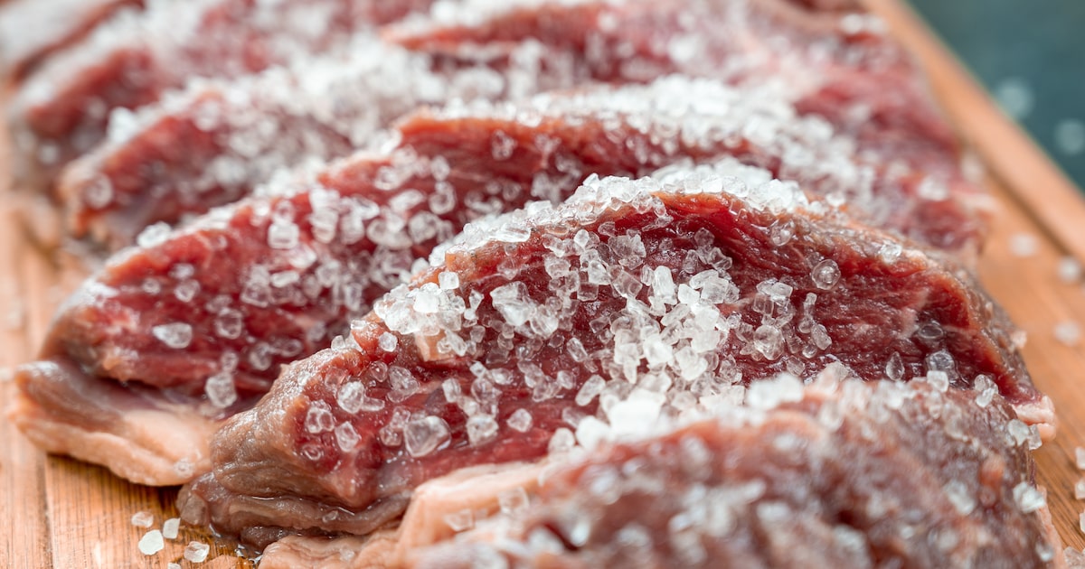 Fatias de picanha crua com sal grosso sobre tábua de madeira