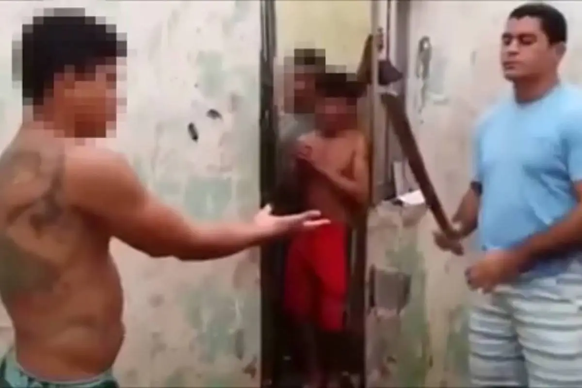 Homem de camiseta azul segura uma espada diante de homem sem camisa