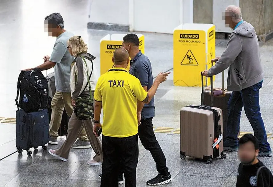 Homens abordam passageiros na área de desembarque do Aeroporto do Galeão