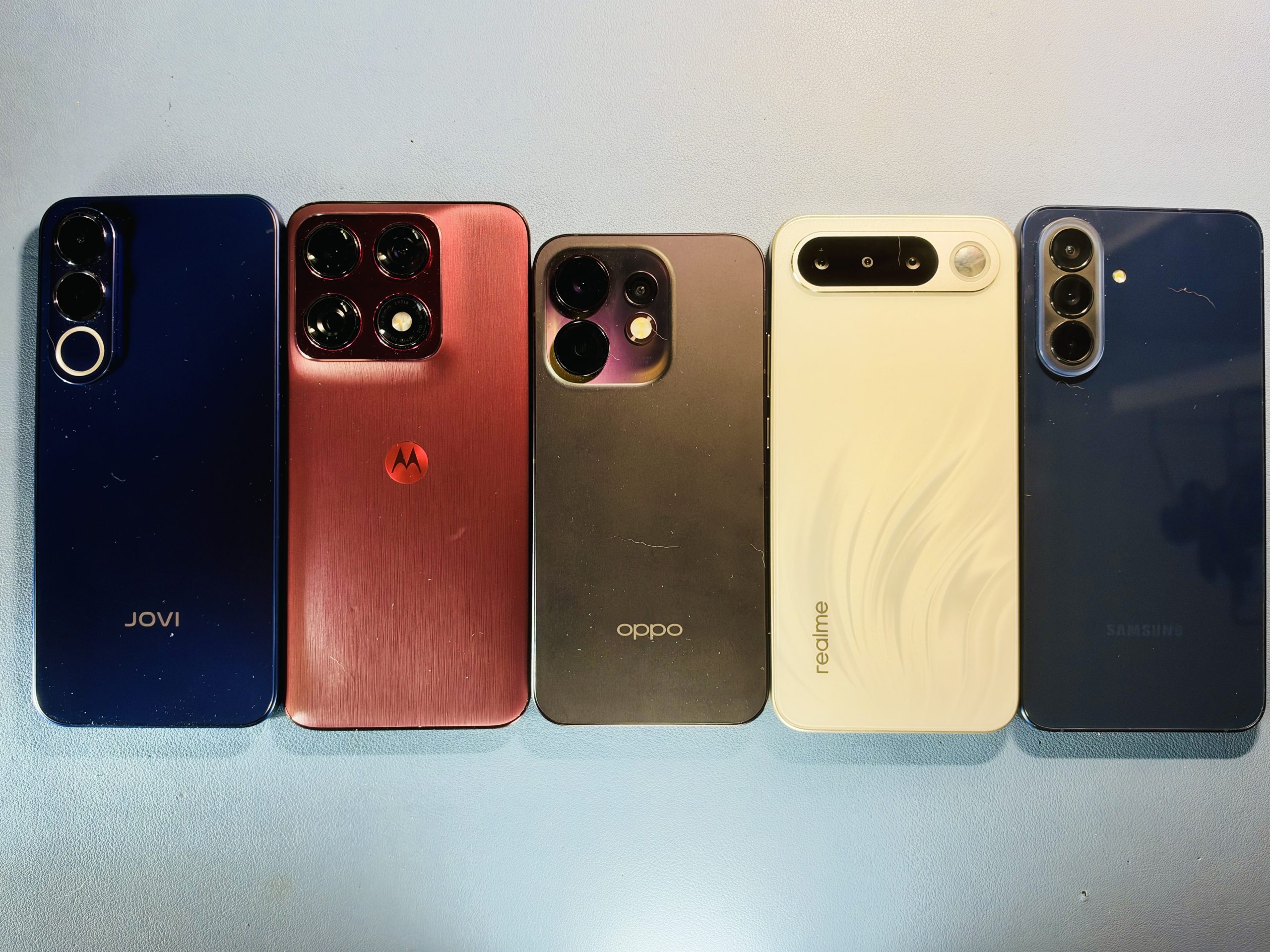 Cinco celulares intermediários alinhados lado a lado