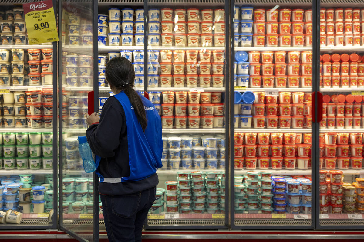 Funcionária organiza produtos em geladeira de supermercado