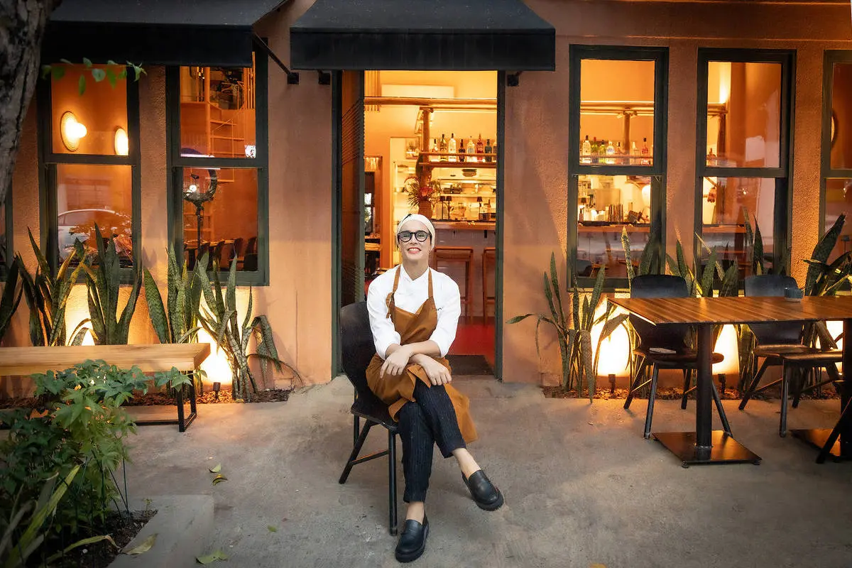 Chef Bel Coelho sentada na entrada do restaurante Clandestino
