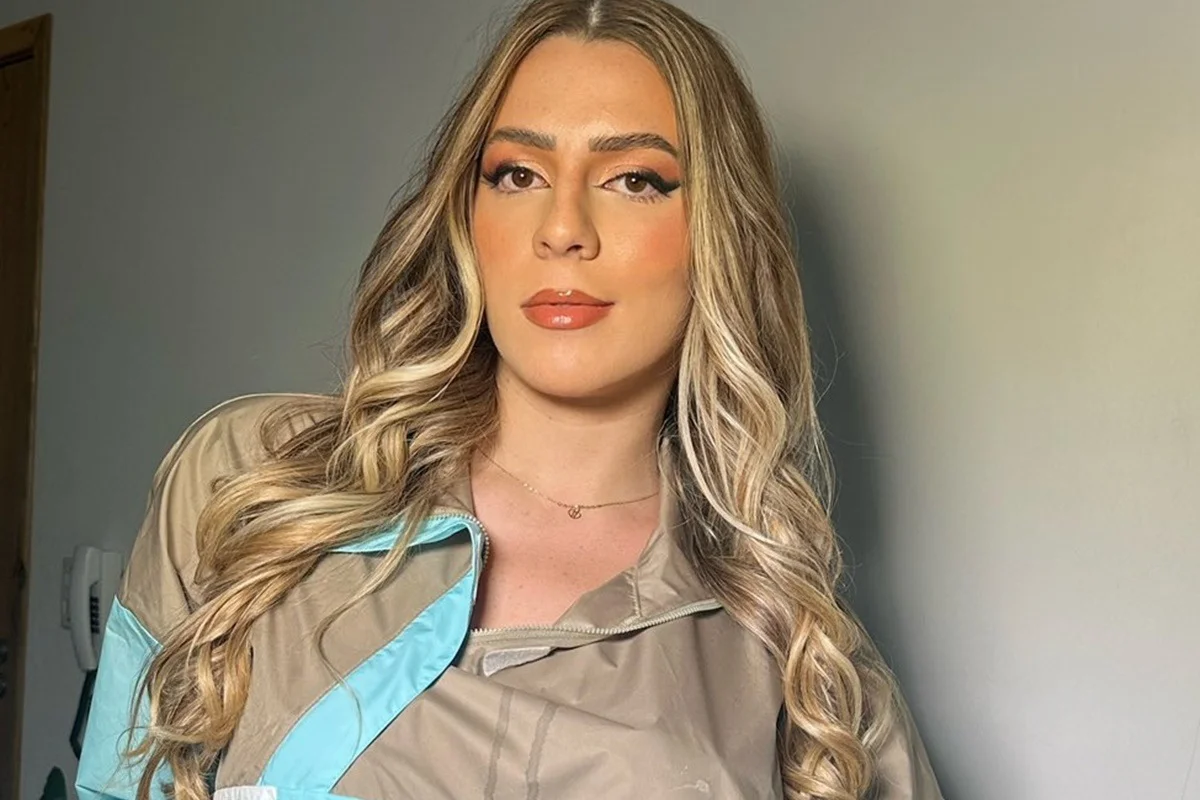 Malévola Alves com roupa cinza e azul e cabelos soltos