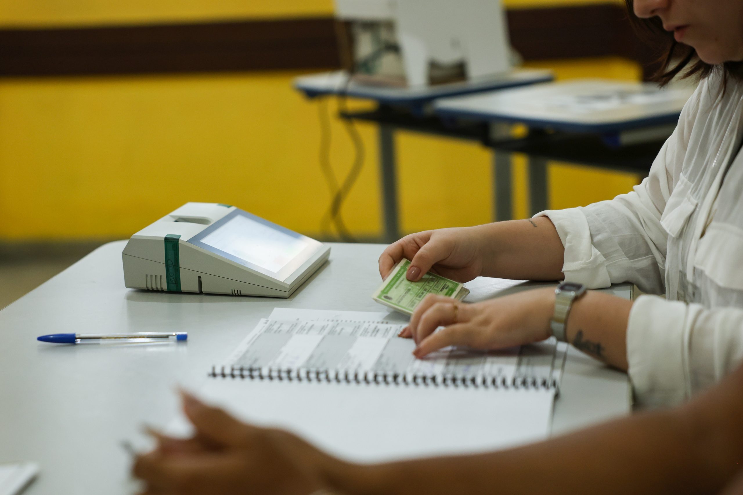 Mesário confere documento de eleitor em seção de votação