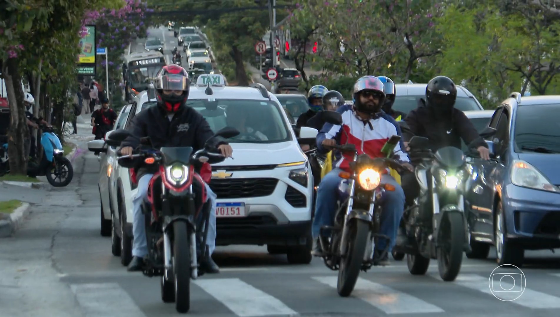 Motocicletas circulam sobre calçada entre pedestres em São Paulo