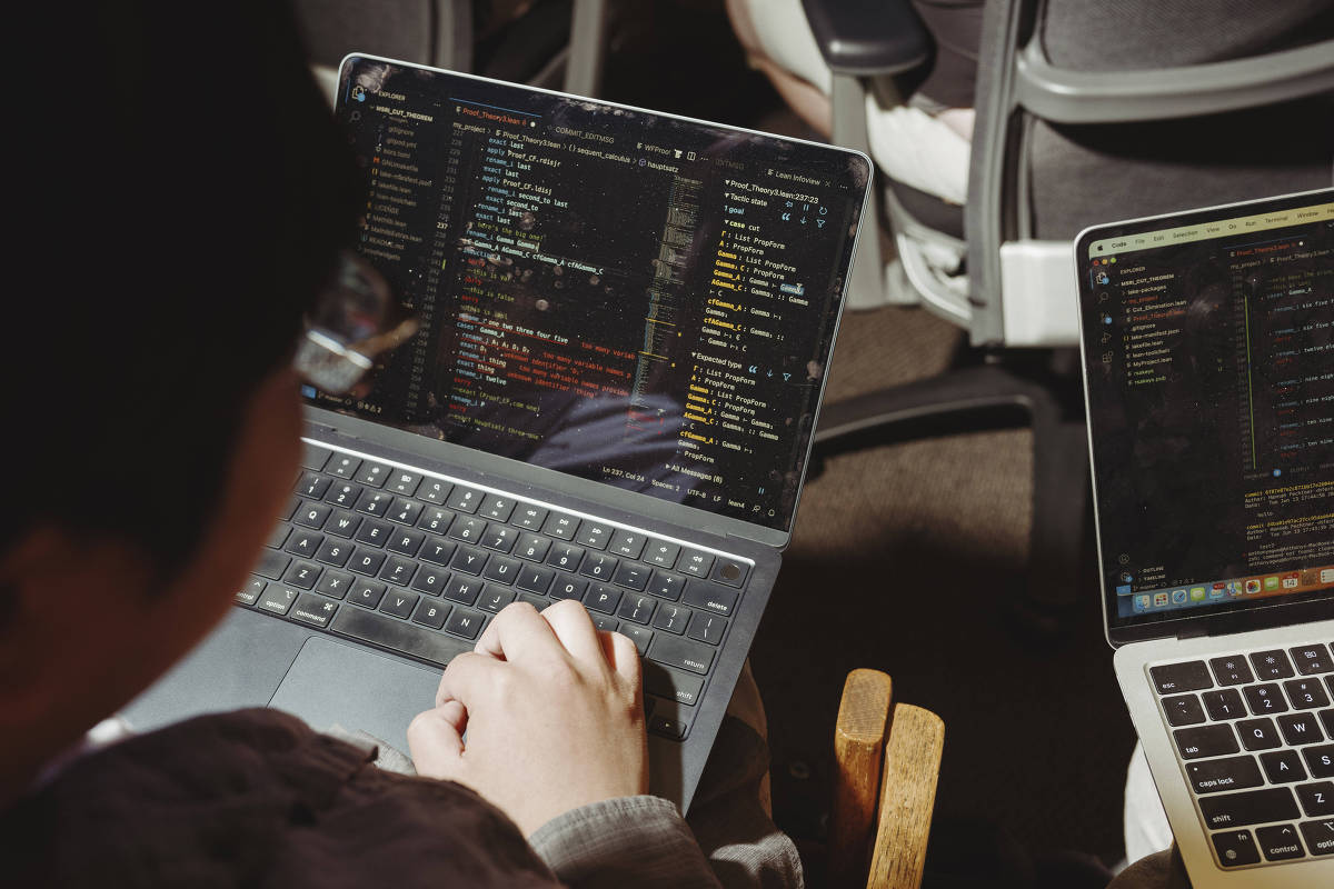 Pessoa usa notebook com código de programação na tela