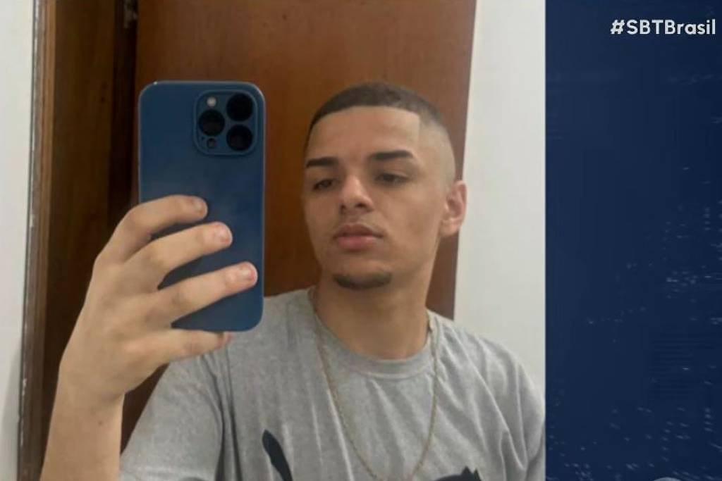 Gustavo Munis de Santana segura um celular diante de espelho