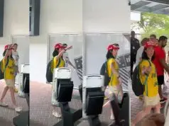 Eleitora de camisa amarela e boné faz gesto com o braço erguido em pátio de escola