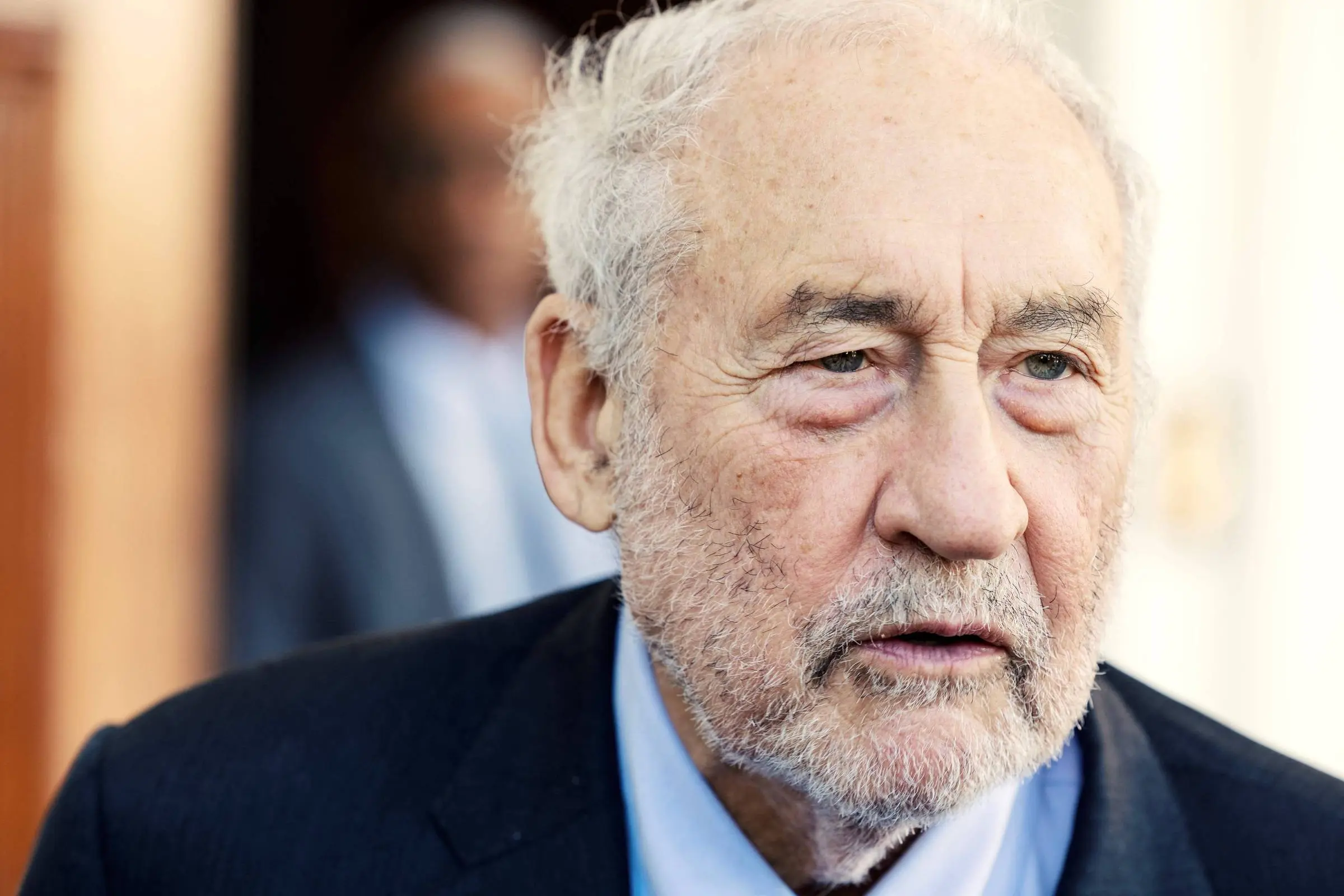 Joseph Stiglitz de terno escuro e camisa azul clara