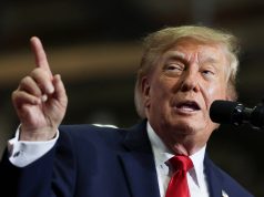 Donald Trump fala ao microfone e levanta o dedo indicador durante comício