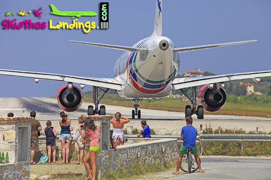 Pessoas próximas à pista enquanto avião se prepara para decolar em Skiathos